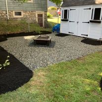 Gravel fire pit area beside a shed